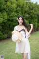 A woman in a white dress holding a straw hat.