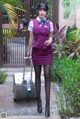 A woman in a purple dress with a suitcase.