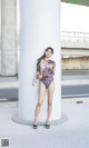 A woman in a bathing suit leaning against a pillar.