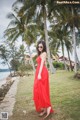 A woman in a red dress standing on a grassy field.