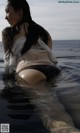 A woman in a white shirt and black panties in the water.