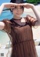 A woman in a brown dress standing on a beach.