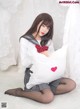 A woman sitting on the floor holding a pillow with a heart on it.