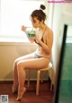 A woman sitting on a stool eating a bowl of food.