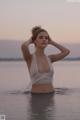 A woman in a white bikini standing in the water.