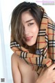 A woman wearing a plaid scarf is posing for a picture.