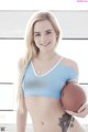 A woman in a blue sports bra holding a football.