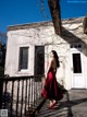 A woman in a red dress standing in front of a building.