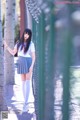 A woman in a school uniform leaning against a fence.