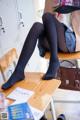 A woman sitting on top of a wooden desk.