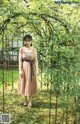 A woman standing in front of a gate in a garden.