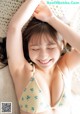 A young girl in a yellow bikini laying on a bed.