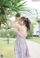 A woman in a floral dress holding a pineapple in her hand.