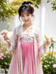 A young girl in a pink and white hanbok holding a flower.