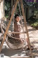 A woman sitting on a swing on a porch.