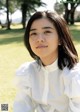 A woman in a white shirt sitting on the grass.