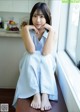 A woman sitting on a window sill with her hand on her chin.