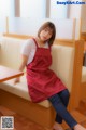 A woman in a red apron sitting on a white couch.