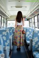 A woman standing in the middle of a bus looking out the window.