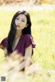 A woman sitting in a field of tall grass.