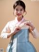 A woman in a blue and white hanbok is posing for a picture.