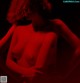A naked woman standing in front of a red background.