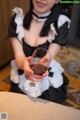 A woman in a maid outfit holding a glass of wine.