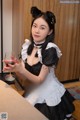 A woman in a maid outfit holding a glass of wine.