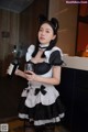 A woman in a maid outfit holding a glass of wine.