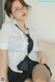 A woman in a white shirt and black skirt sitting on a couch.