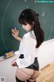 A woman in a white shirt and black skirt standing in front of a blackboard.