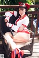 A woman in a red and white outfit sitting on a chair.