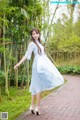 A woman in a blue dress standing on a brick walkway.