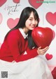 A woman in a red sweater holding a red heart.