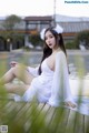 A woman in a white dress sitting on a wooden dock.