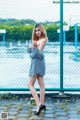 A woman standing in front of a chain link fence.