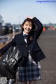 A woman in a school uniform standing next to a bike.